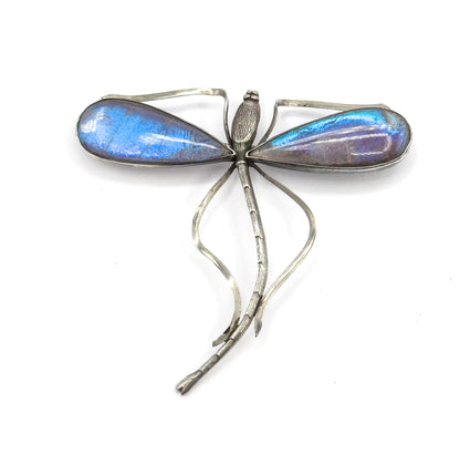 Upright from directly above with the beaded head at the top, a domed teardrop wing to each side in blue and violet, and the open wire frames curving down around the long segmented tail.