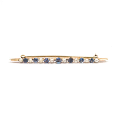 Straight-on full-length front view with the bar lying level and the pin stem closed behind it, hinge at the left and catch at the right, the alternating sapphires and seed pearls in one even row.