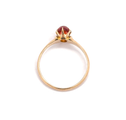 Upright head-on view through the circle of the slim shank, the oval orange cabochon sitting in its pronged setting at the top with an open gallery beneath.
