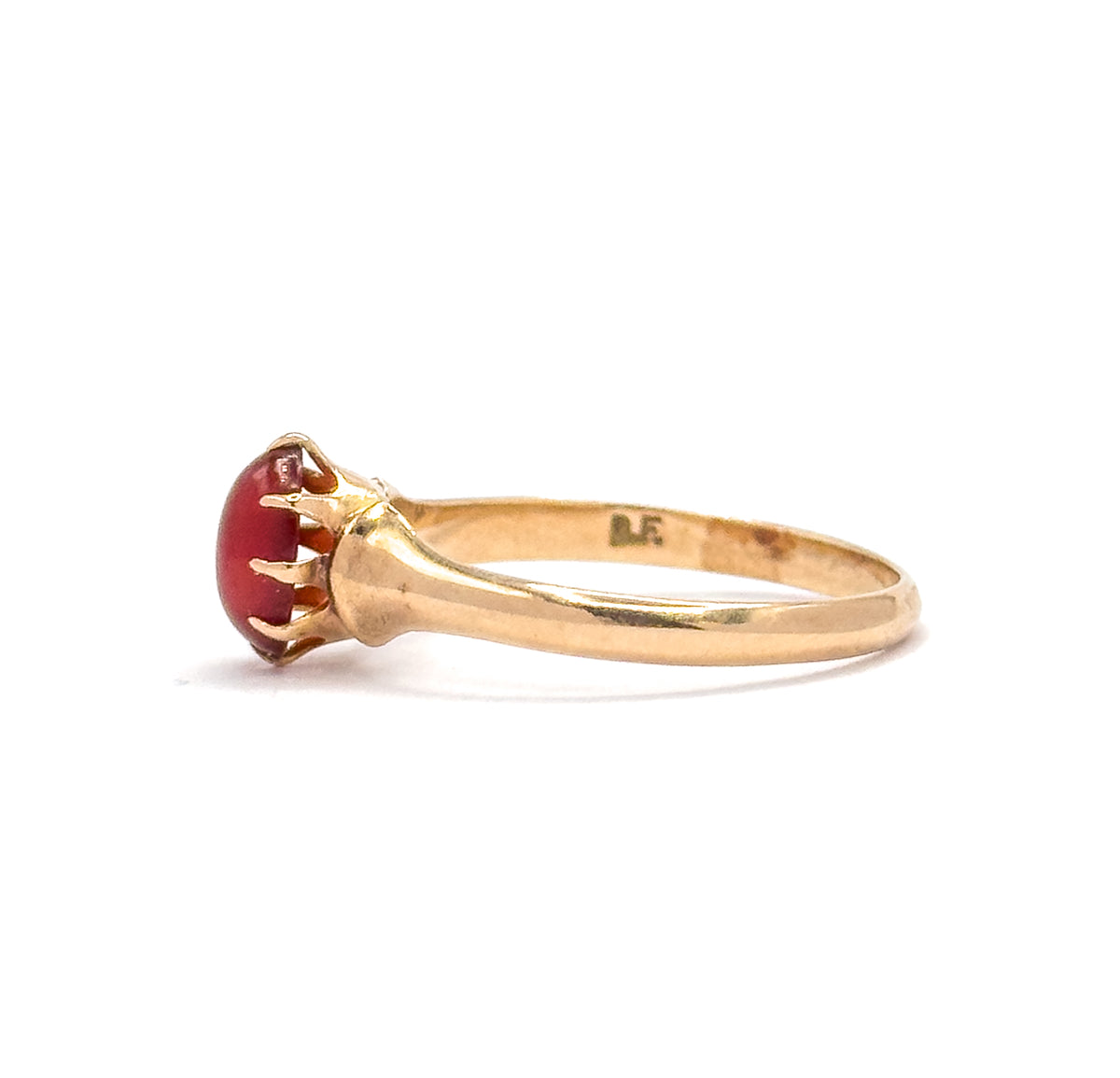 Side view from the opposite direction, with small maker's initials stamped inside the yellow gold shank and the oval orange cabochon in its pronged setting at left.