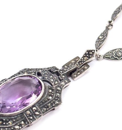 Steeply angled close view from the side, emphasising the stepped marcasite-set links and their hinged joins between pendant top and chain, with the amethyst edge-on at lower left.