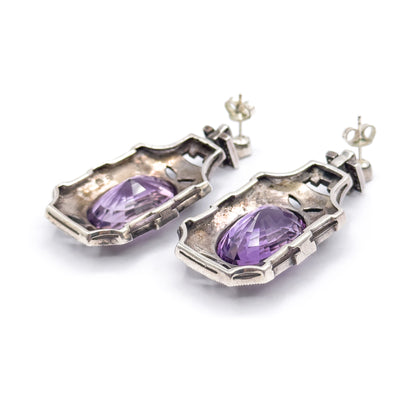 The reverse of both earrings, showing the open-backed sterling silver bezels with the amethyst pavilions visible through them, plus the post and butterfly fittings behind.