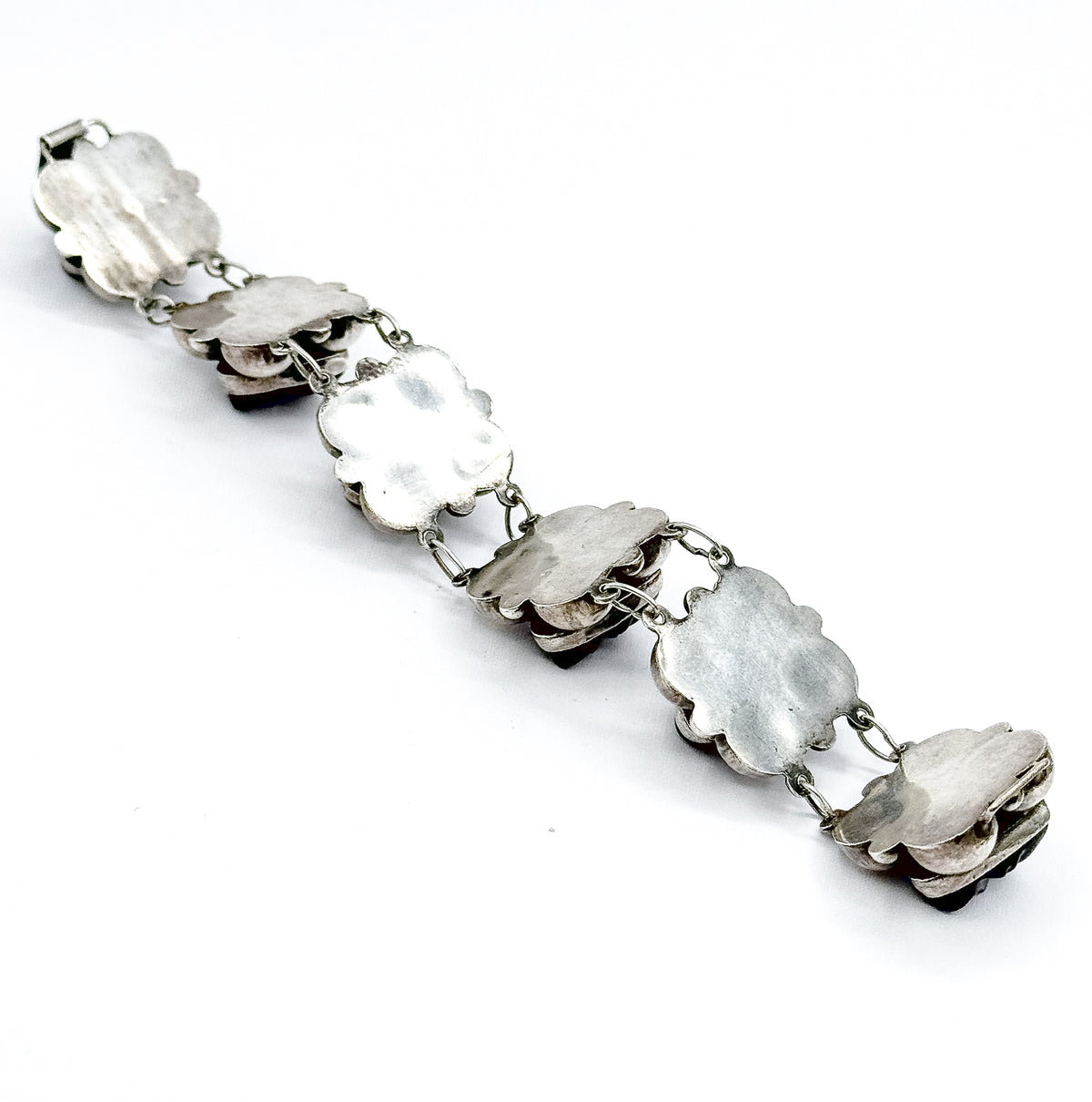Reverse view laid out diagonally on white, showing the smooth hollow backs of the scalloped stations, the oval links between them, and the clasp fitting at one end.