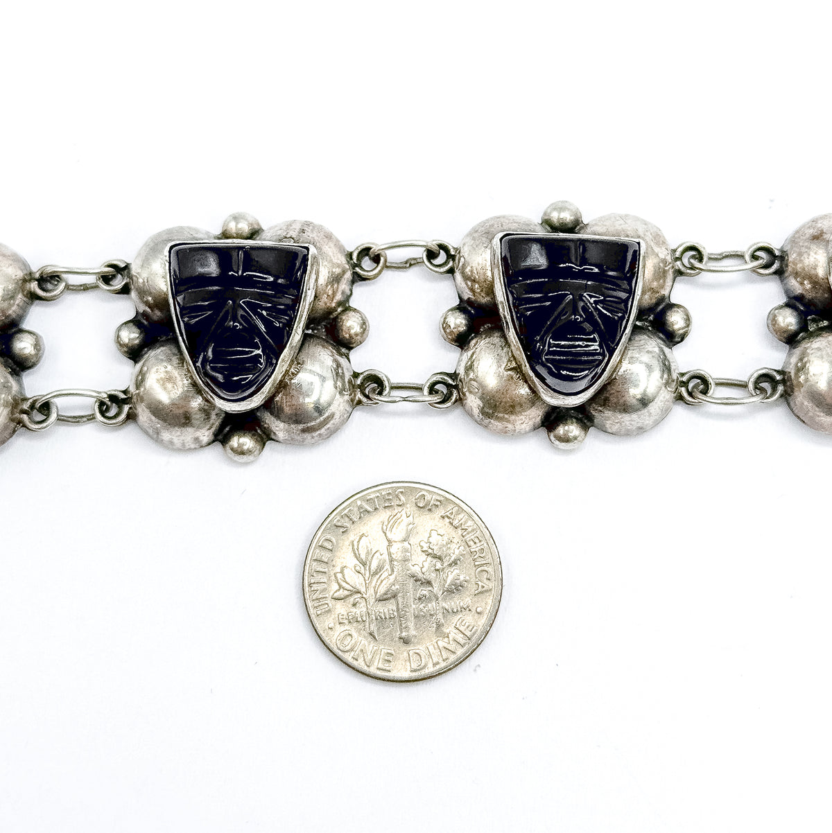Two carved onyx face stations and their silver domes photographed above a dime placed on the white background, giving a direct sense of scale.