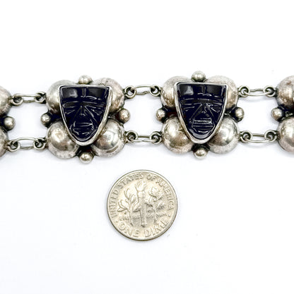 Two carved onyx face stations and their silver domes photographed above a dime placed on the white background, giving a direct sense of scale.