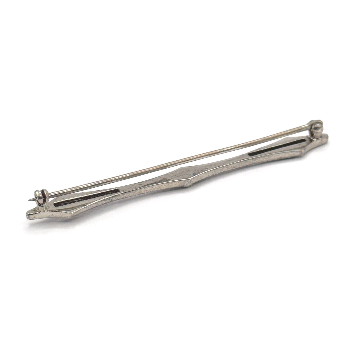Art Deco filigree bar brooch in sterling silver, shown from the back at a diagonal on a white background, with the long pin stem, hinge and catch visible along the slim tapered bar.