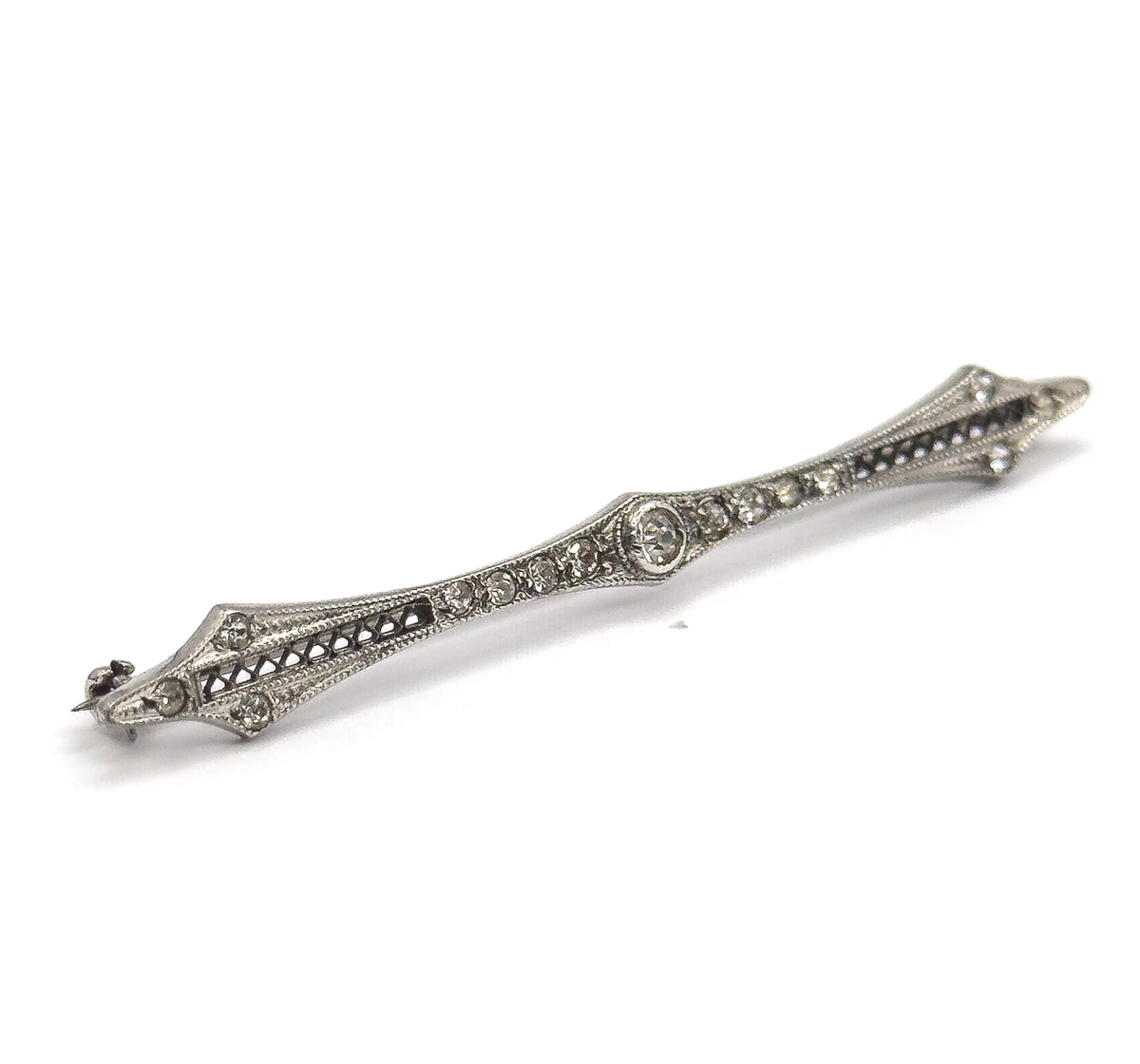 Angled three-quarter view from the front, the bar rising across the frame so the filigree openwork, rows of paste gems and diamond-shaped points catch the light in relief.