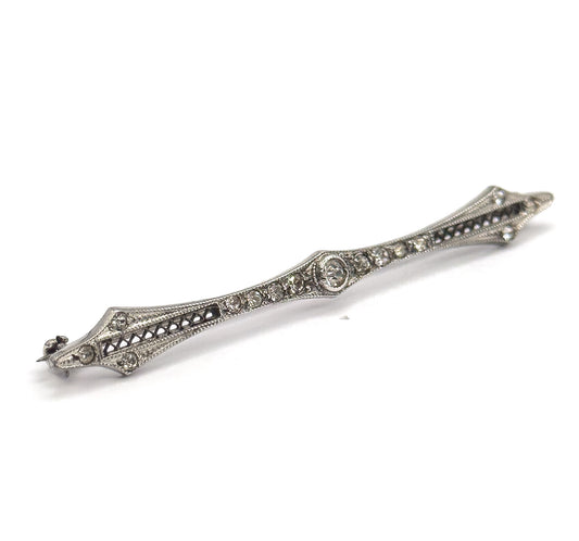 Angled three-quarter view from the front, the bar rising across the frame so the filigree openwork, rows of paste gems and diamond-shaped points catch the light in relief.
