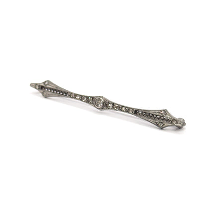 Steeply foreshortened view along the length of the bar, the near point closest to the camera so the slim depth of the filigree frame and the raised central bezel stand out.