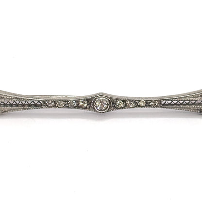 Tight close-up of the brooch's midsection, the central paste gem in its round bezel flanked by graduated rows of small pastes above triangular filigree piercing, the bar running off both edges.