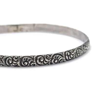 Close crop on one side of the band, filling the frame so each raised swirl and the darkened recesses between them can be seen in detail against white.