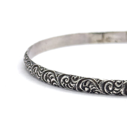 A tighter end-on crop where the band narrows into the distance, showing how slim the sterling silver is in profile and how the smooth inner surface meets the swirled outer face.