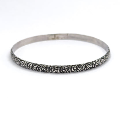 Seen flat on from the front, the whole oval bangle sits upright on white with the swirled outer face running unbroken around the near rim and the plain inner wall visible behind.