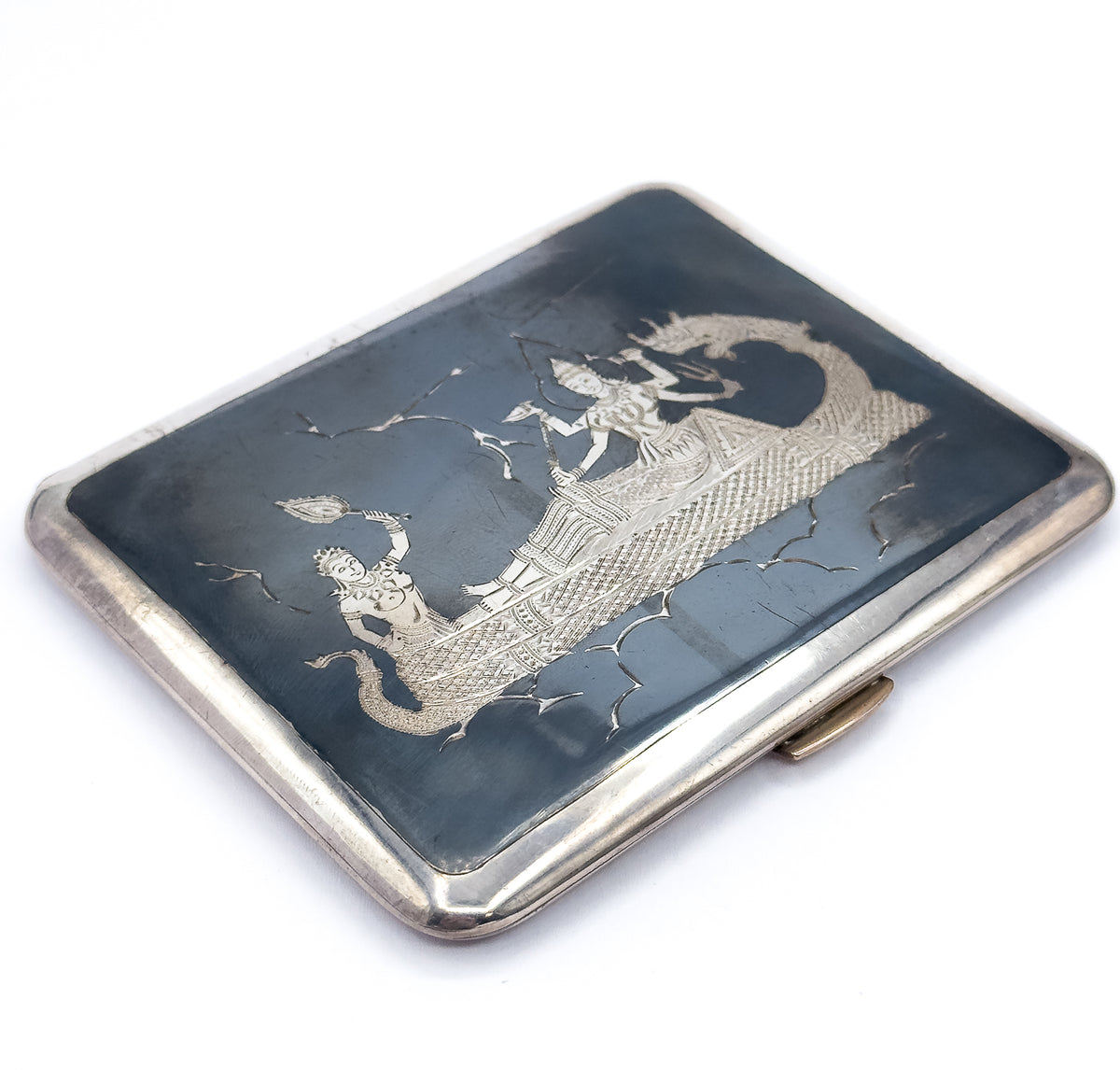 Seen almost flat from above, the whole rectangle fills the frame with its rounded corners and slate-black engraved panel, the bright silver rim widening along the near edge beside the clasp.