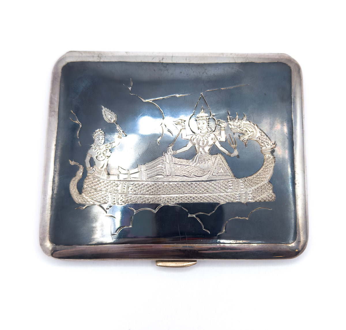Squared-on from directly above with the lid upright, the engraved boat scene centred in the slate-black panel and the small light-coloured clasp thumbpiece projecting from the bottom edge.