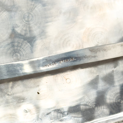Extreme close-up inside the case, where a narrow raised bar across the swirl-polished light metal bears a small stamped mark in block letters.
