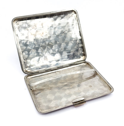 The case lying fully open on white, both swirl-polished light-metal halves visible with the central hinge, the retaining bar across the lower half, and the clasp thumbpiece at its edge.