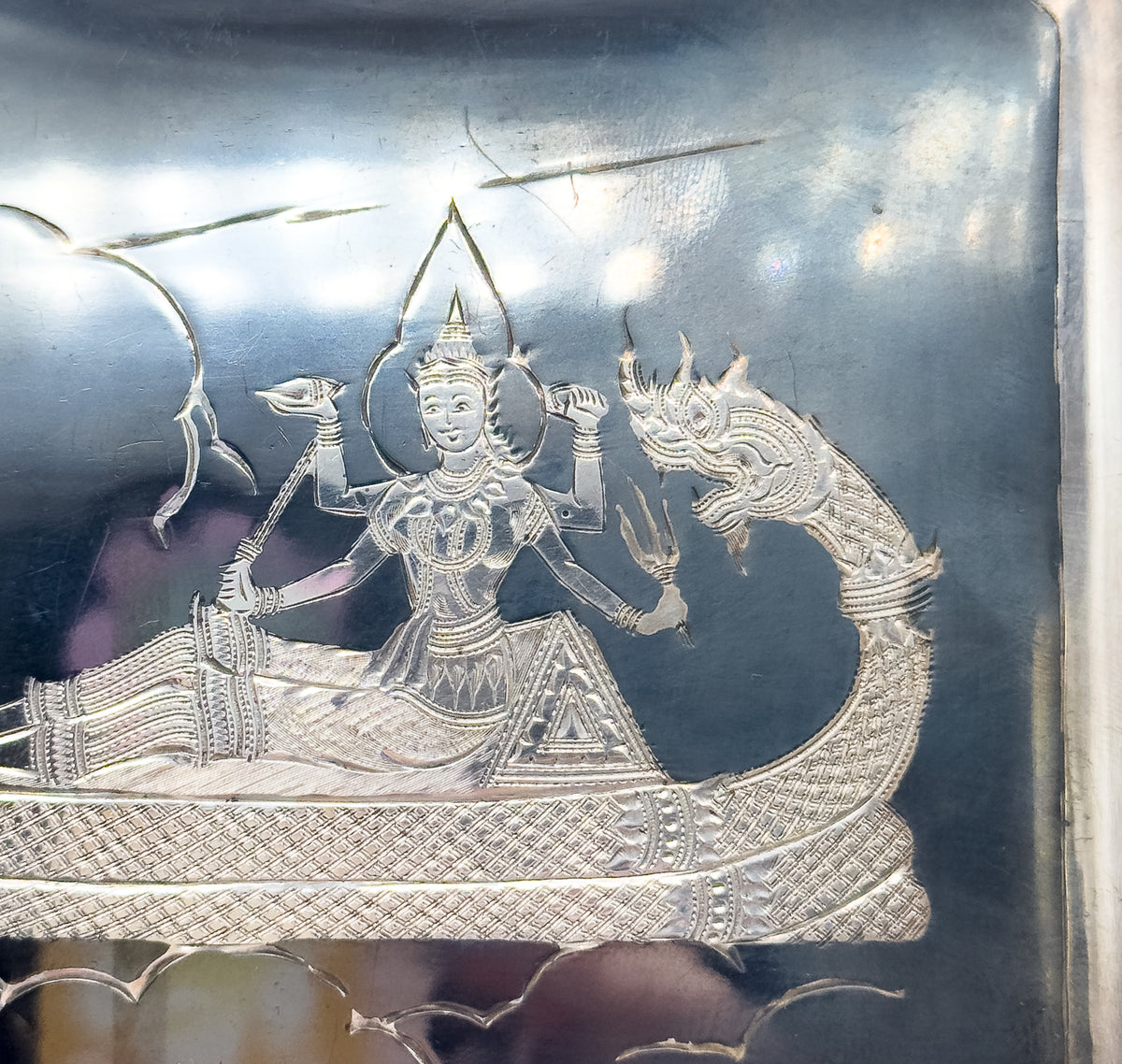 Mid-Century Siam style engraved sterling silver case, shown in close crop of its dark niello face where a crowned figure rides a boat with a mythical beast-head prow.