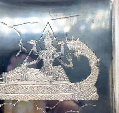 Mid-Century Siam style engraved sterling silver case, shown in close crop of its dark niello face where a crowned figure rides a boat with a mythical beast-head prow.