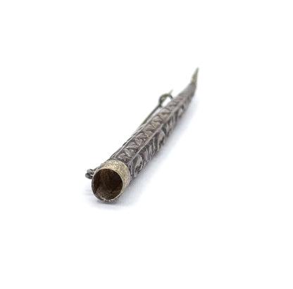 Looking down into the open mouth of the cone at lower left, the hollow interior and collared rim visible, with the repoussé body receding to the pin stem's point at upper right.