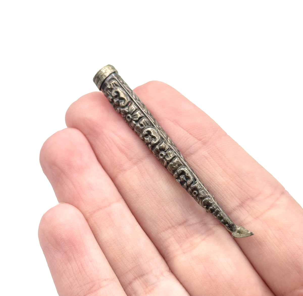 An Art Nouveau repoussé cone brooch in sterling silver, shown resting across the fingers of an open hand to convey its slim, tapering size, with the pin stem extending past the tip.