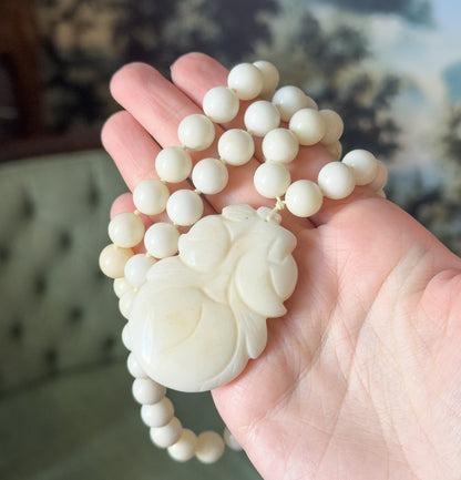 Cupped in an open palm, the coiled strand and carved gourd pendant together fill the hand, giving a clear sense of the necklace's substantial scale and weight.