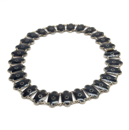 The full necklace laid flat in a complete circle on white, showing every enamel station around the loop and the clasp fitting at the right-hand side.