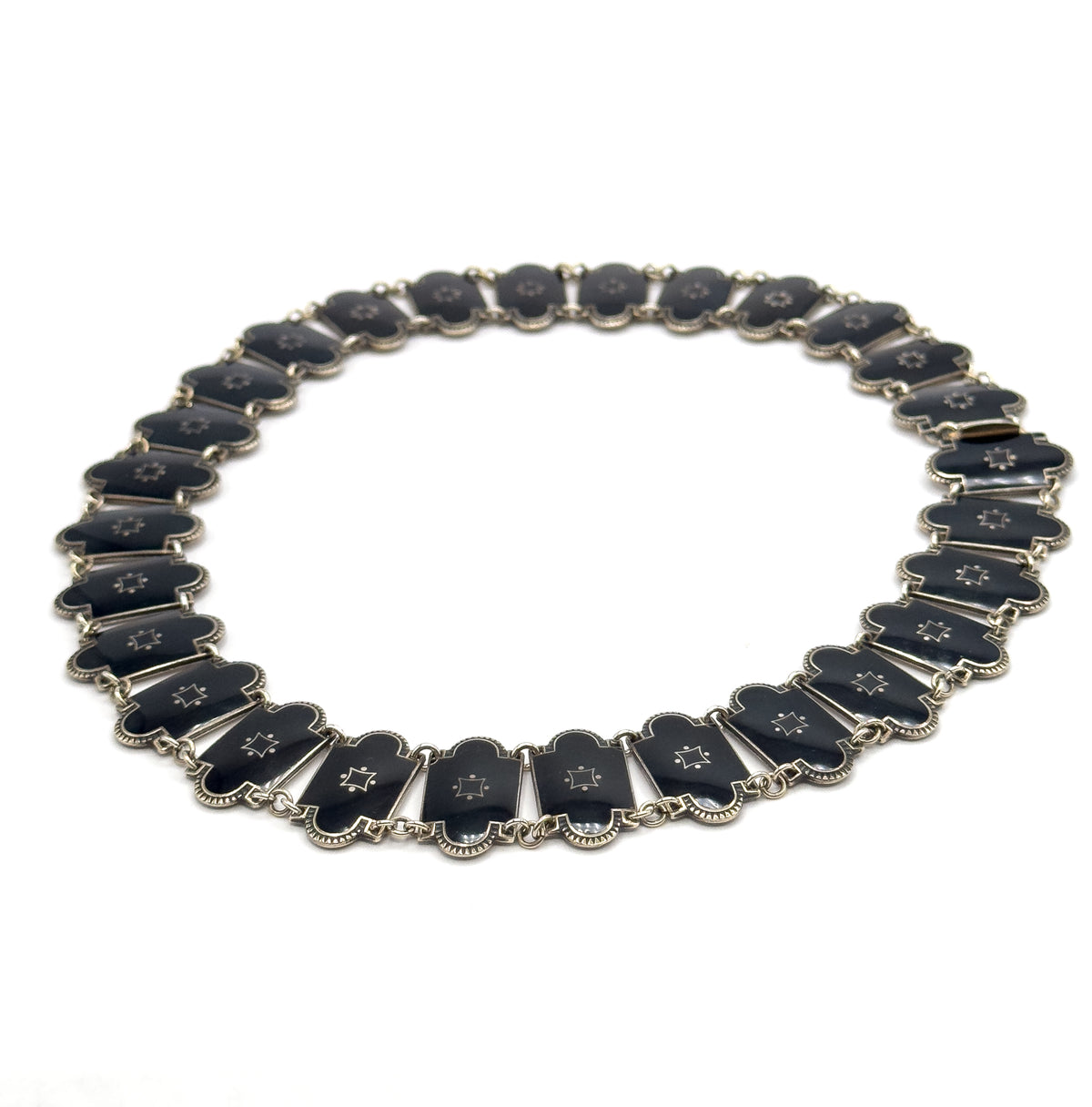 The whole necklace closed into an oval on white, seen at a low tilt so the far links recede and the near ones stand slightly on edge, with the clasp fitting visible at the upper right.