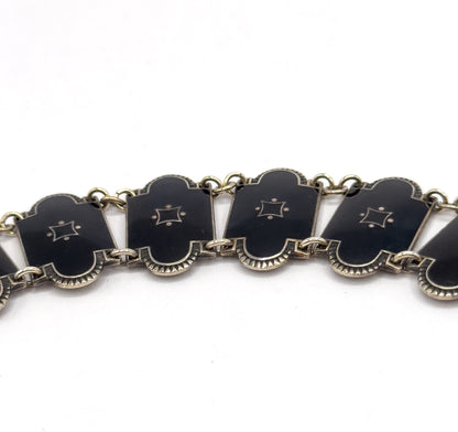 A tight close-up of five enamel links in a row, each showing the small four-pointed star with dots and the fan-like fluted edge along its lower border, joined by round jump rings.