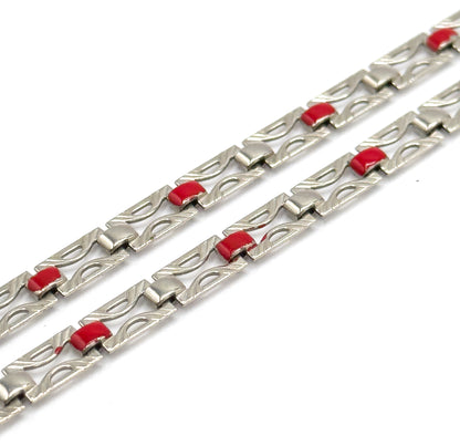 Two runs of chain recede steeply into the distance against white, each pierced link's engraved outline and small squared connector sharp in front and softening away toward the top.