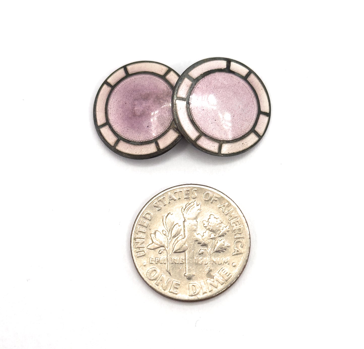 Two overlapping discs are pictured above a dime, the coin giving a clear sense of scale against the lavender guilloche centres and pale enamel panels.