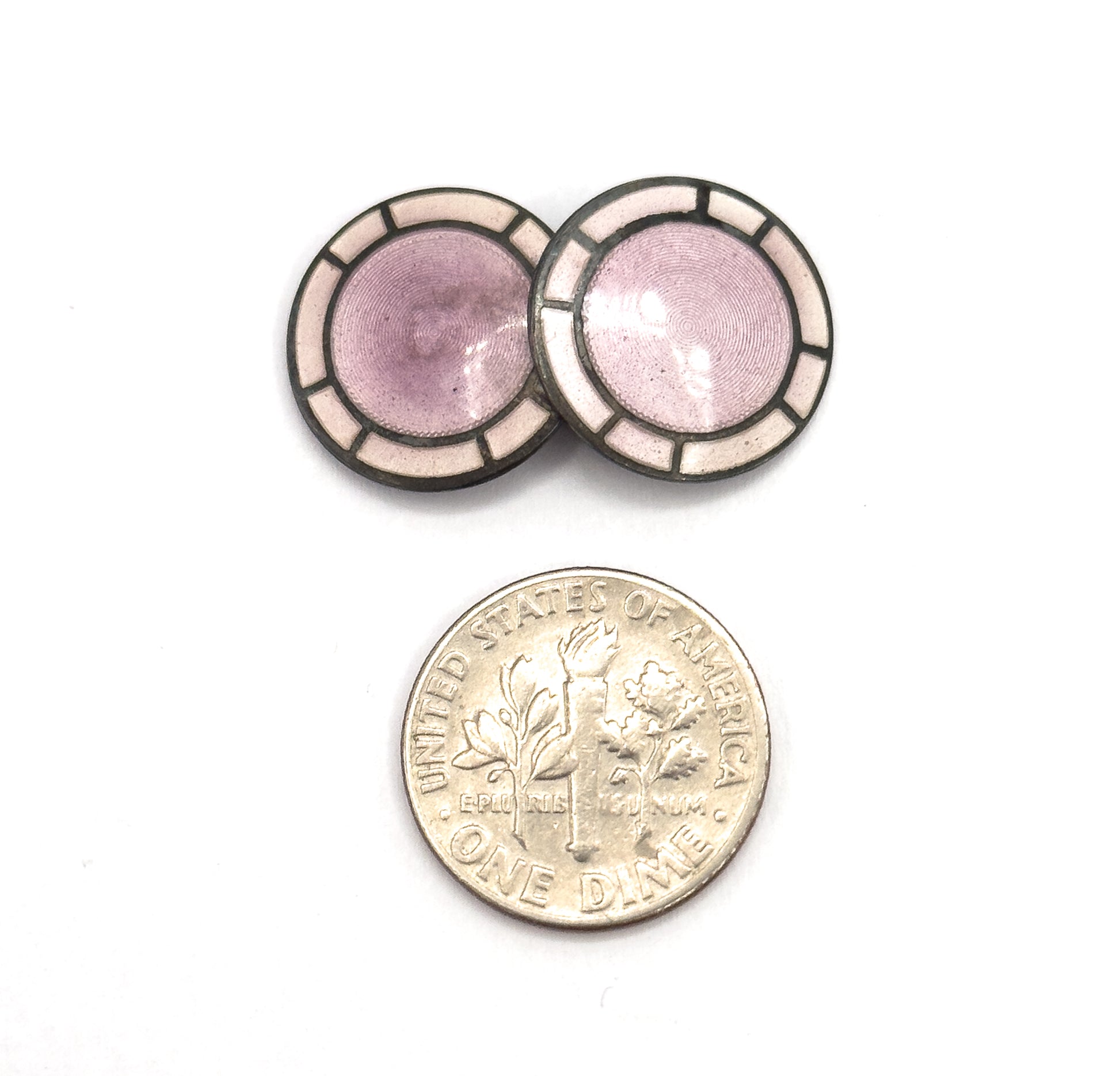 Two overlapping discs are pictured above a dime, the coin giving a clear sense of scale against the lavender guilloche centres and pale enamel panels.