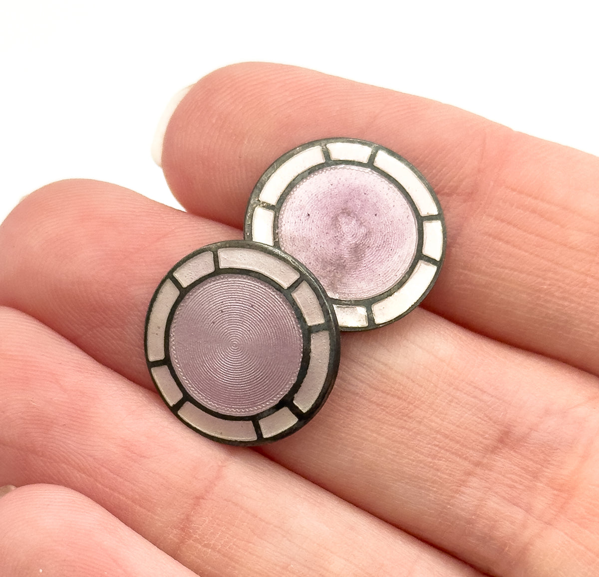 Art Deco lavender guilloche enamel cufflinks in sterling silver, the two circular discs shown resting on fingertips, which gives a sense of their small scale.