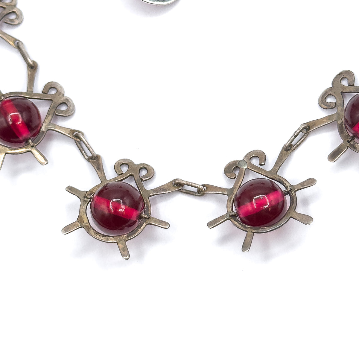 Four atomic insect stations dip in a shallow curve at the base of the necklace, their cranberry glass beads held by slim prongs between curled antennae and radiating sterling legs.