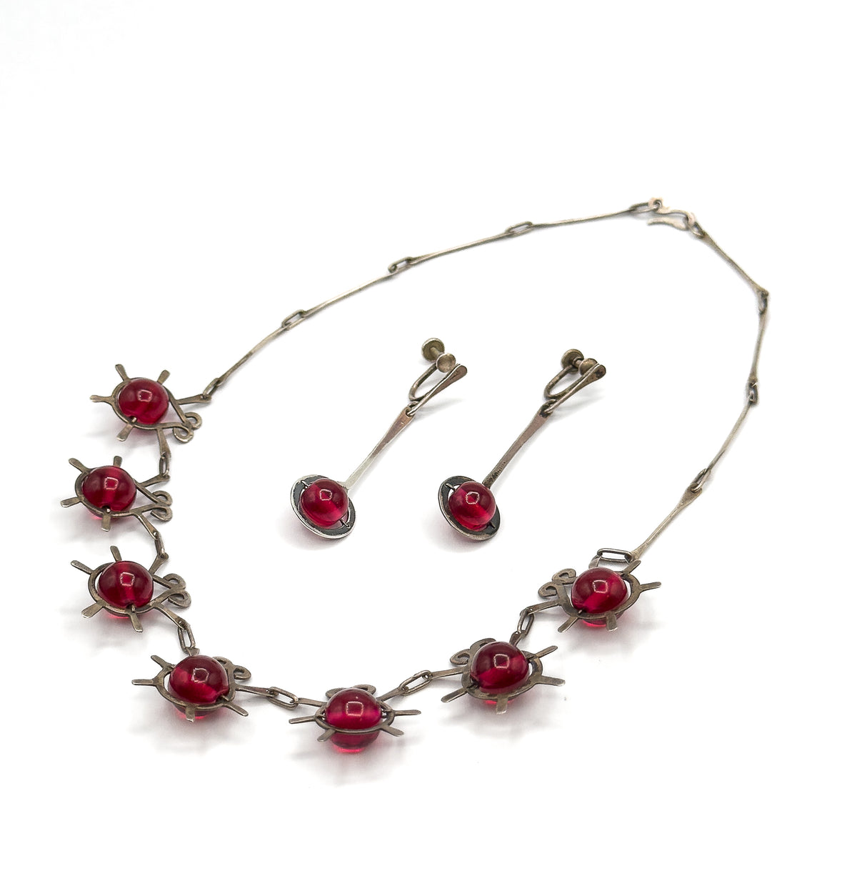 The whole set laid out together: the necklace's full sterling chain looping open to its hook clasp, eight atomic insect stations along the lower curve, with both earrings resting inside.