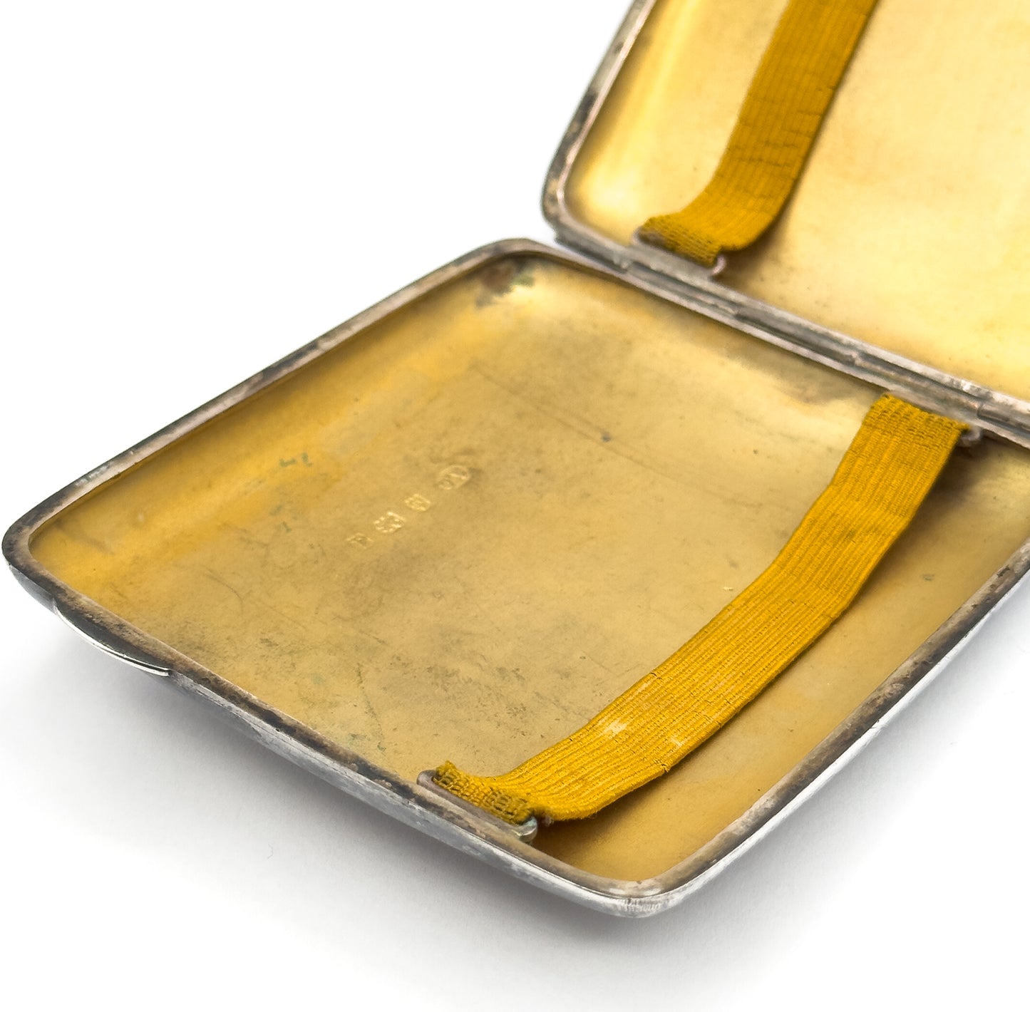 Looking down into the open case at an angle, with a row of small stamped marks visible on the gilt floor of the lower half.