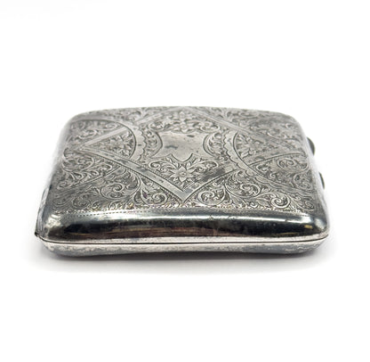 The case viewed end-on, showing its depth and the plain rounded side wall beneath the engraved lid, with darker patina along the rim.