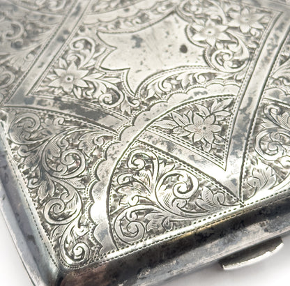 A close crop of one engraved corner, filling the frame with scrolling foliage, small flowers, and the fine stippled shading worked between them.