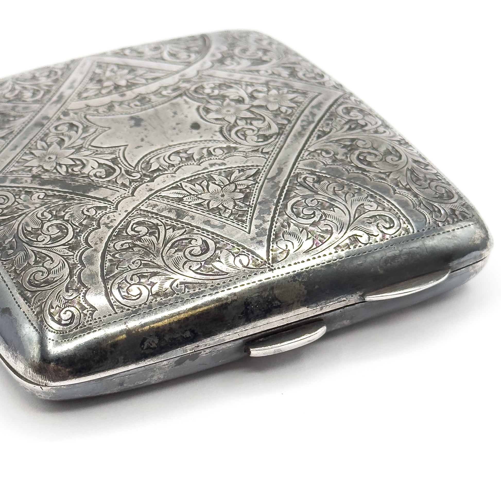 The closed case seen from its lower edge, showing the hinge knuckles and thumbpiece along the side beneath the engraved lid.