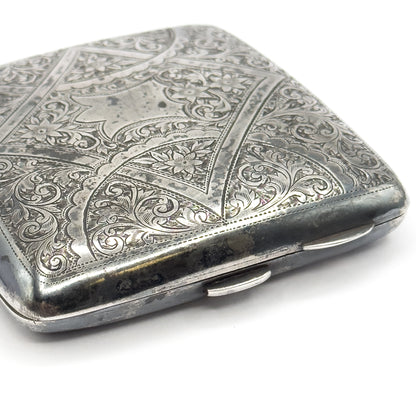 The closed case seen from its lower edge, showing the hinge knuckles and thumbpiece along the side beneath the engraved lid.
