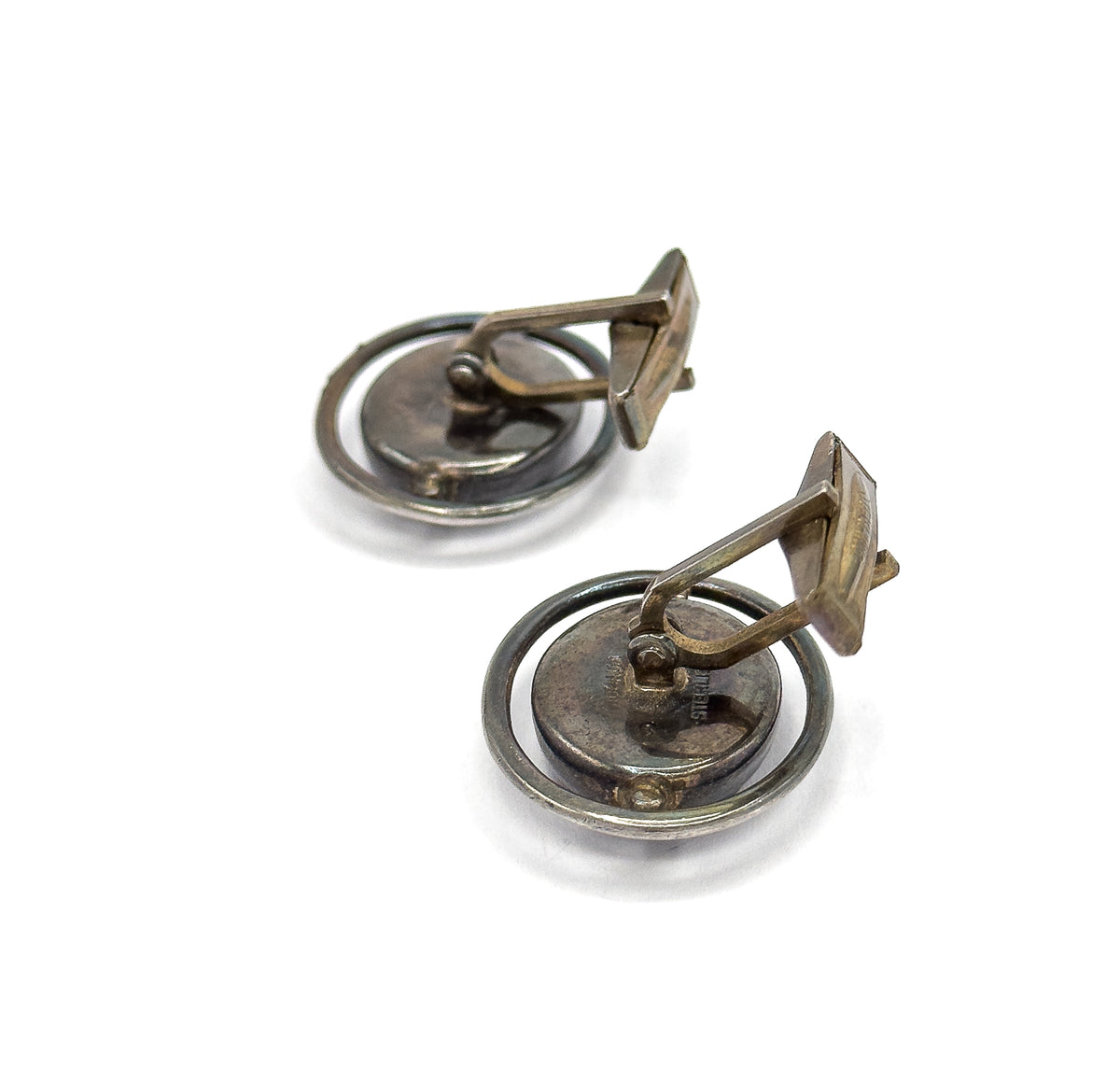 Angled three-quarter rear view of the pair, the toggle bars lifted upright on their hinge pivots away from the oval backs, with the encircling silver hoops seen from behind.