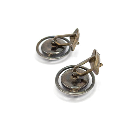 Angled three-quarter rear view of the pair, the toggle bars lifted upright on their hinge pivots away from the oval backs, with the encircling silver hoops seen from behind.