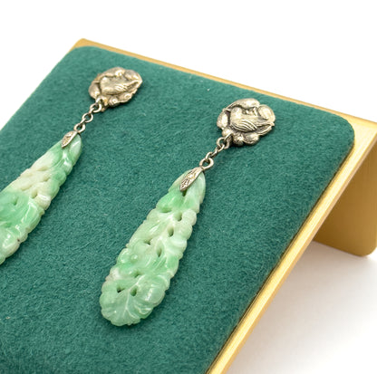 Angled close view on a green felt display stand, showing the embossed bird top, short chain link and pierced flower carving on each long minty green drop.