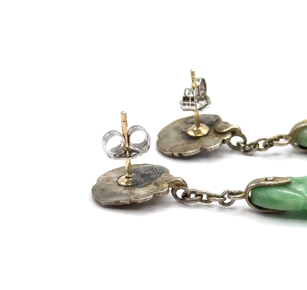 Reverse view of the two bird tops against white, showing the light-coloured posts and butterfly backs, the textured metal behind each top, and the chain links running to the jade drops.