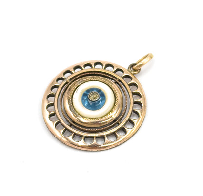 The pendant tilted face-up on a white background, the scalloped openwork rim and milgrain rings catching light as the bail angles to the upper right.
