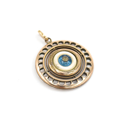The pendant face-on against white with the bail at upper left, showing the full ring of scalloped cut-outs evenly around the mother of pearl and blue glass centre.