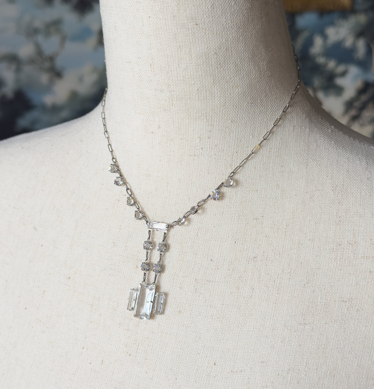 Angled closer view showing the small round faceted stones spaced along the chain and the twin parallel bars of the drop ending in three rectangular stones set side by side.