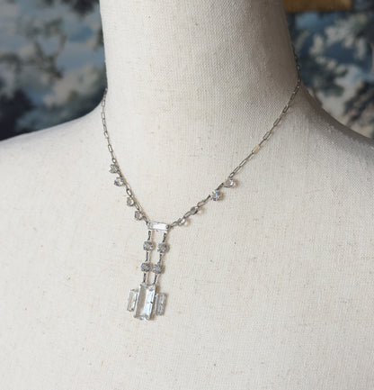 Angled closer view showing the small round faceted stones spaced along the chain and the twin parallel bars of the drop ending in three rectangular stones set side by side.