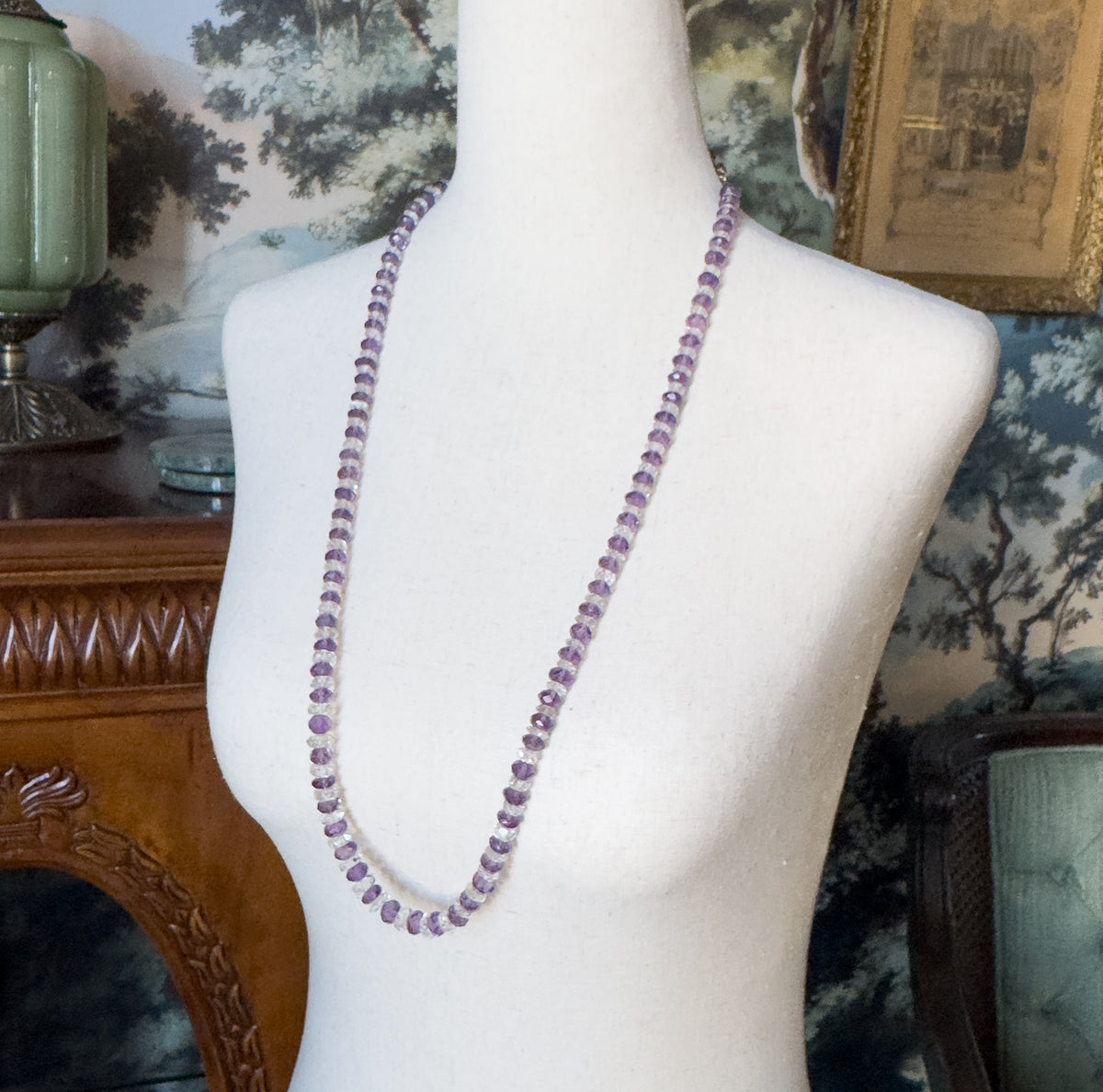An Art Deco necklace of alternating purple amethyst and colourless rock crystal faceted rondelle beads, shown draped at the neck of a pale fabric display bust.