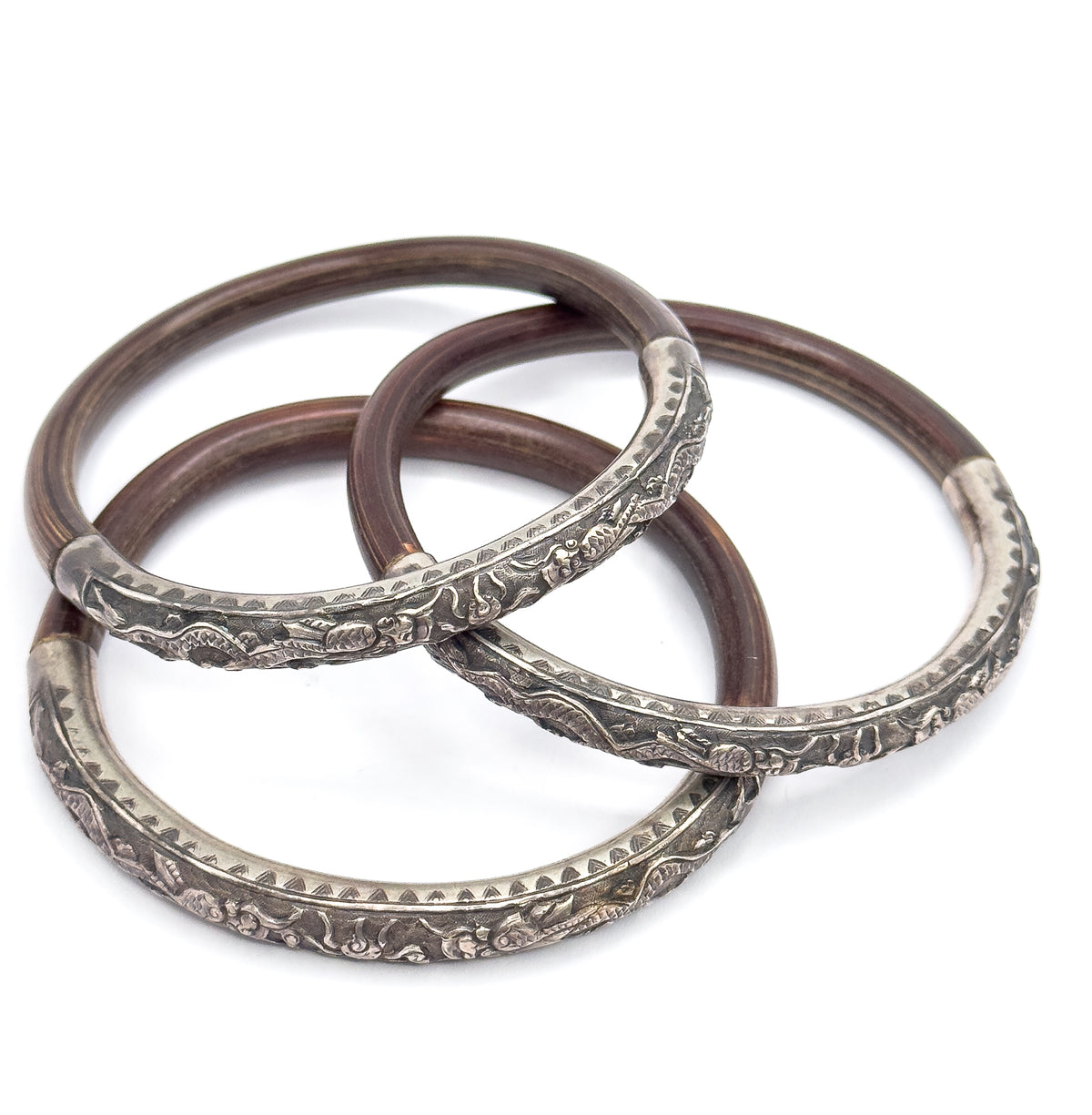 Three bangles laid out loosely in a fanned triangle rather than a neat stack, each full circle visible so the silver sections and their joins with the brown wood can be followed right around.